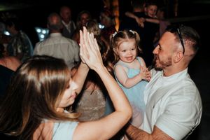 A group of people dancing and celebrating together at a lively indoor party or reception.