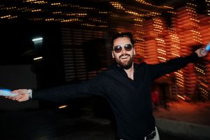 People dancing and celebrating in a dimly lit nightclub with orange lighting and atmospheric effects.