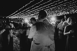 A romantic black and white dance scene under twinkling string lights at an evening reception.