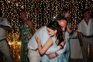 A couple shares a romantic dance under twinkling string lights at an evening wedding reception.