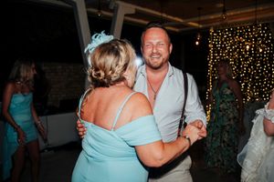 A couple dances together at an evening reception with twinkling lights in the background.