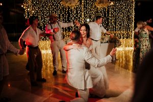 Wedding guests dance and celebrate on a dimly lit dance floor with twinkling lights and fog effects in the background.