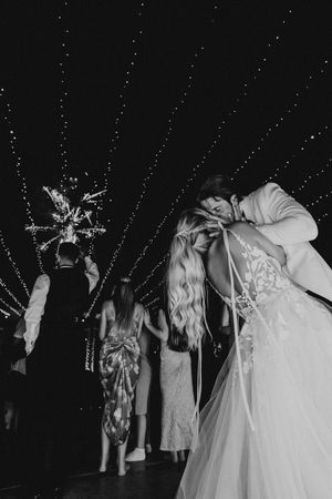 Black and white photo of a wedding dance under twinkling lights with a disco ball overhead.