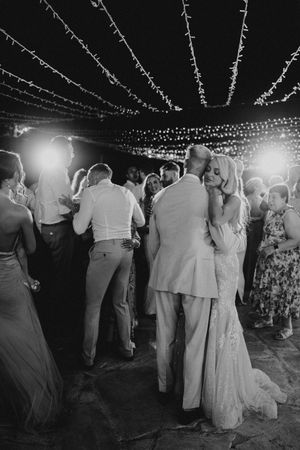 Couples dancing at an outdoor evening reception under twinkling string lights in black and white photography.