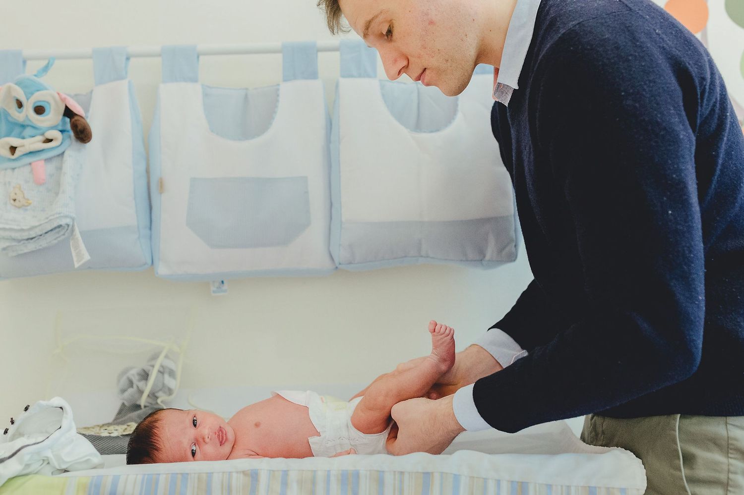 Ein liebevoller Moment, in dem jemand einem neugeborenen Baby auf einem Wickeltisch im Kinderzimmer die Windel wechselt.