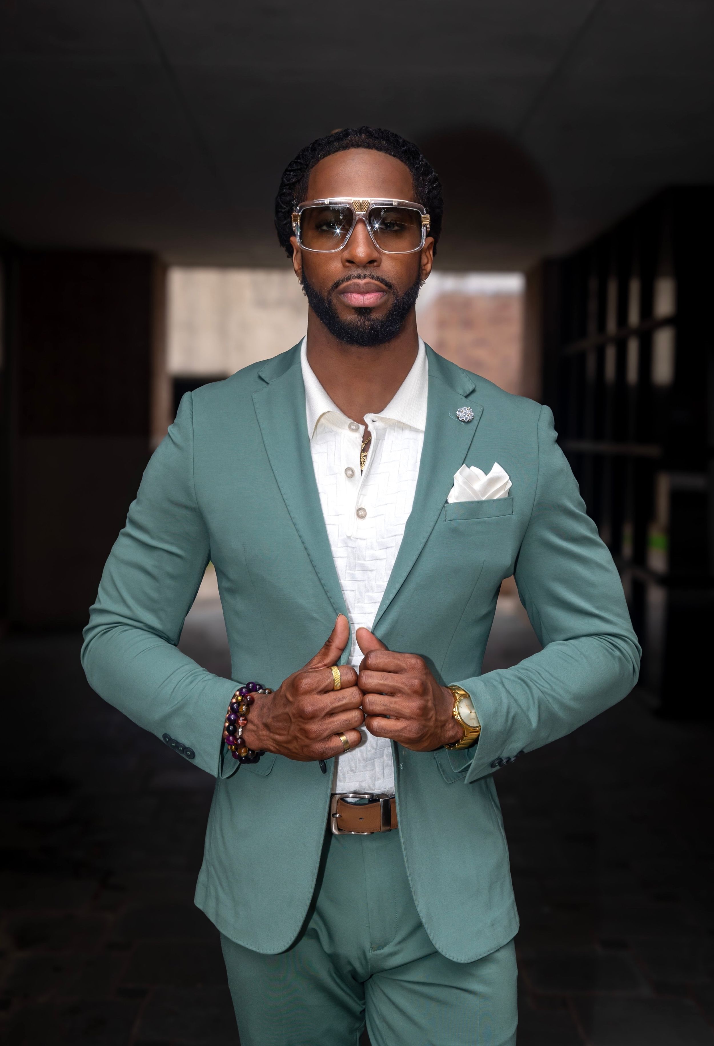 Fashion portrait showing mint green suit with white pocket square and statement sunglasses.