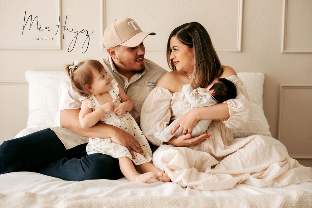 Intimate lifestyle family photography session on white bedding with soft natural light.