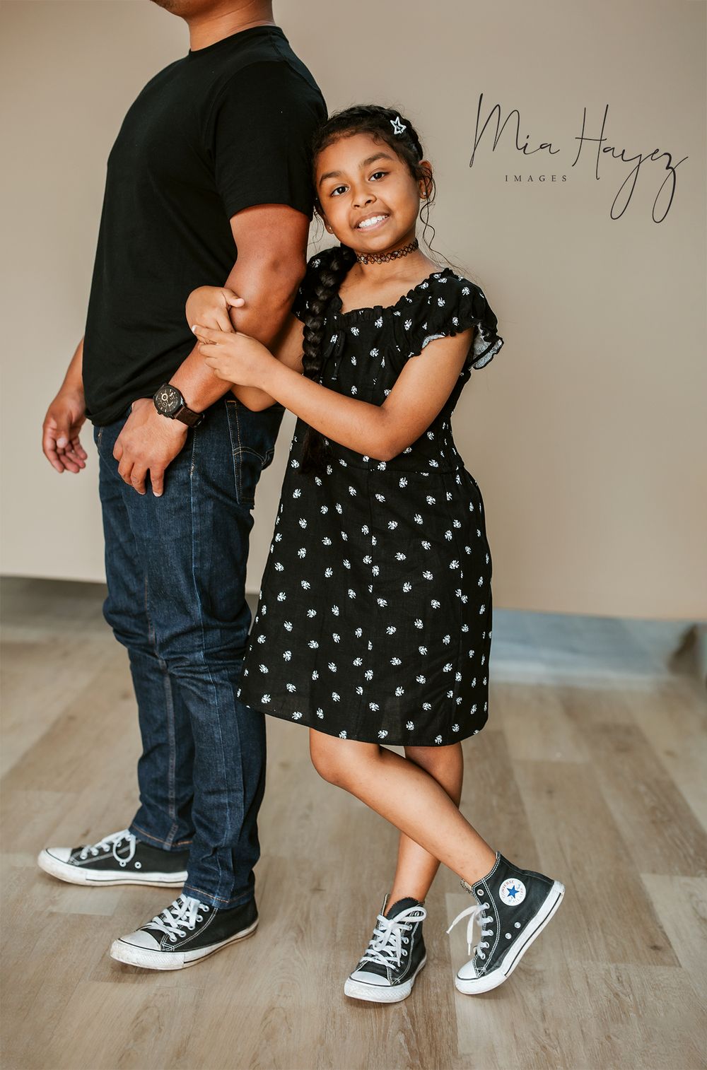 Close-up of black and white polka dot dress and matching Converse shoes on wooden floor.
