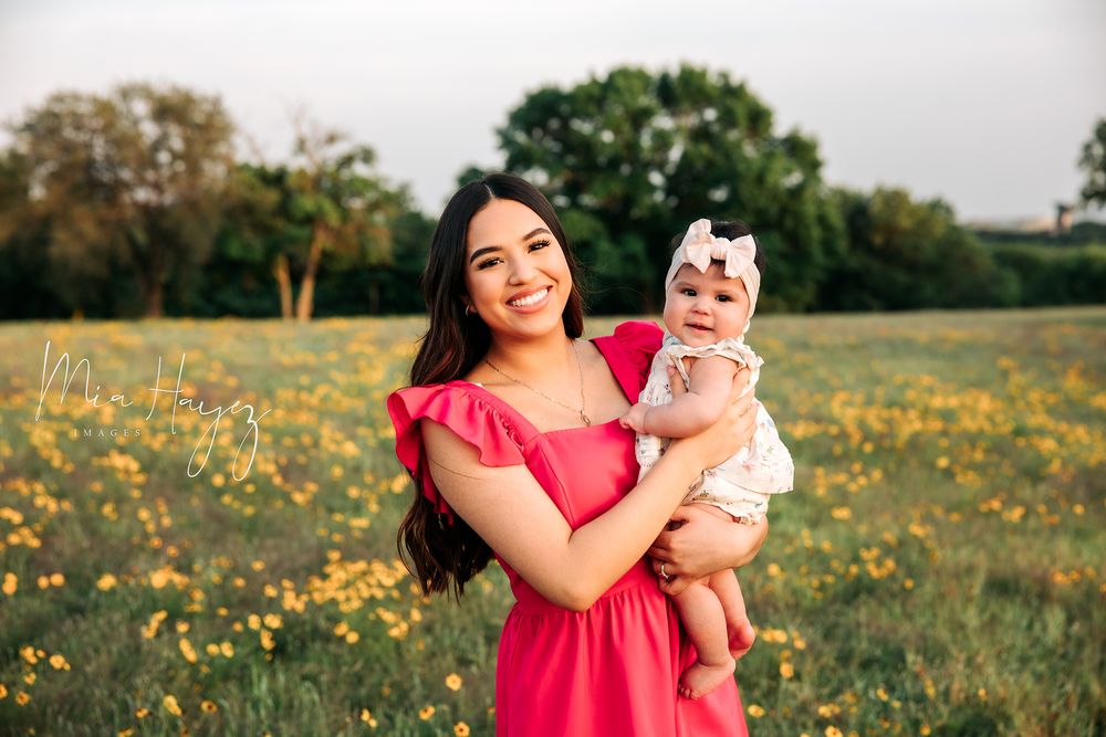 Mother and child share joyful moments in a sunlit field of yellow wildflowers at golden hour.