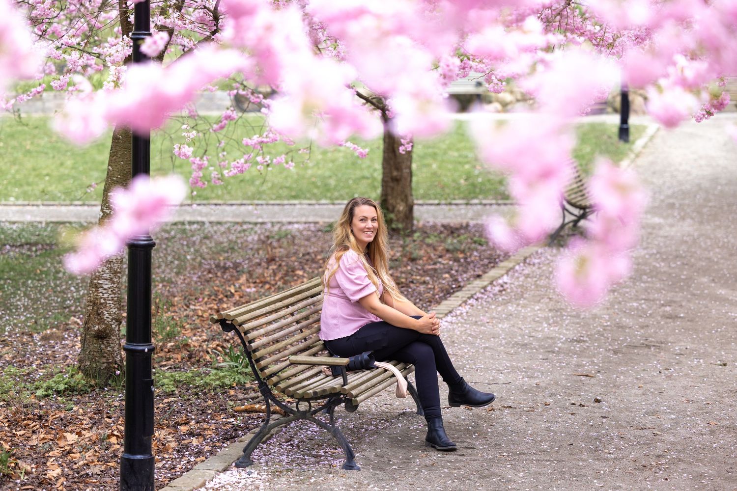 Jag, Erica, sitter på en parkbänk med rosa körsbärsblom i förgrunden