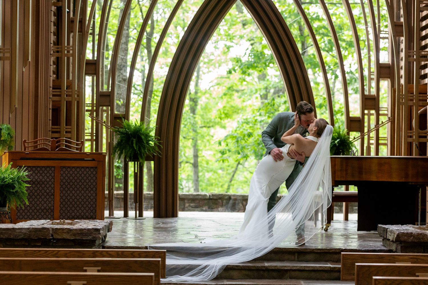 Wedding couple shares a romantic moment in a beautiful gothic-style chapel with arched wooden beams and natural light.