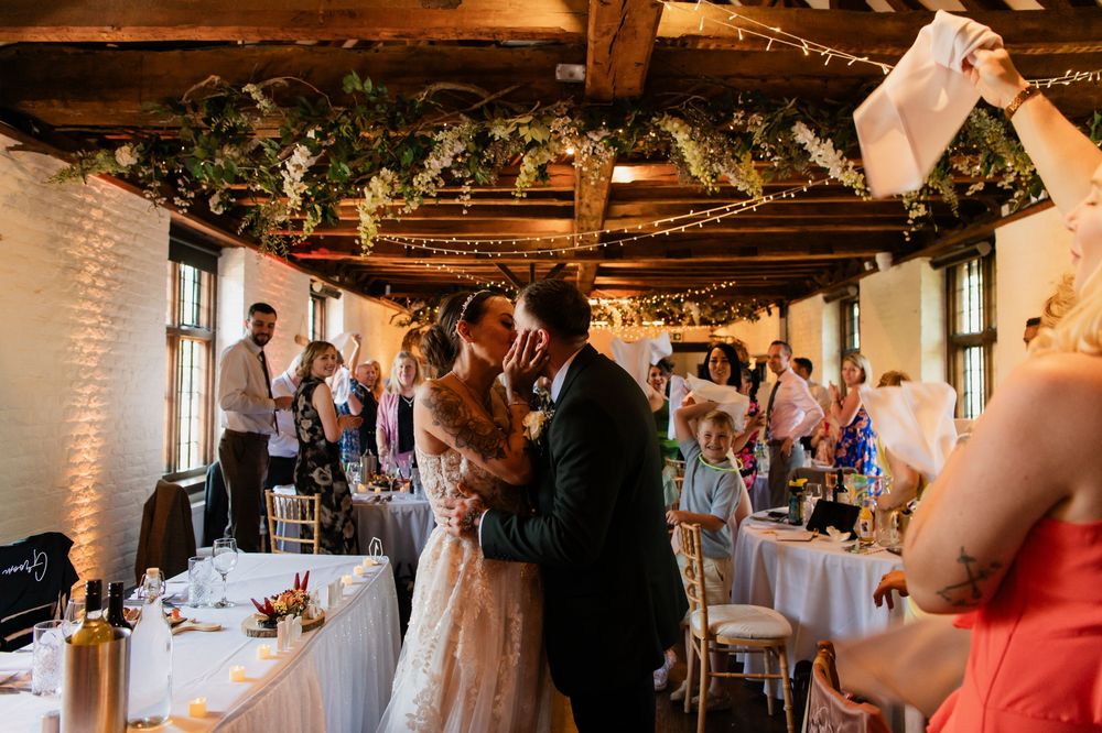 Wedding reception venue decorated with string lights and rustic wooden beams creates warm ambiance.