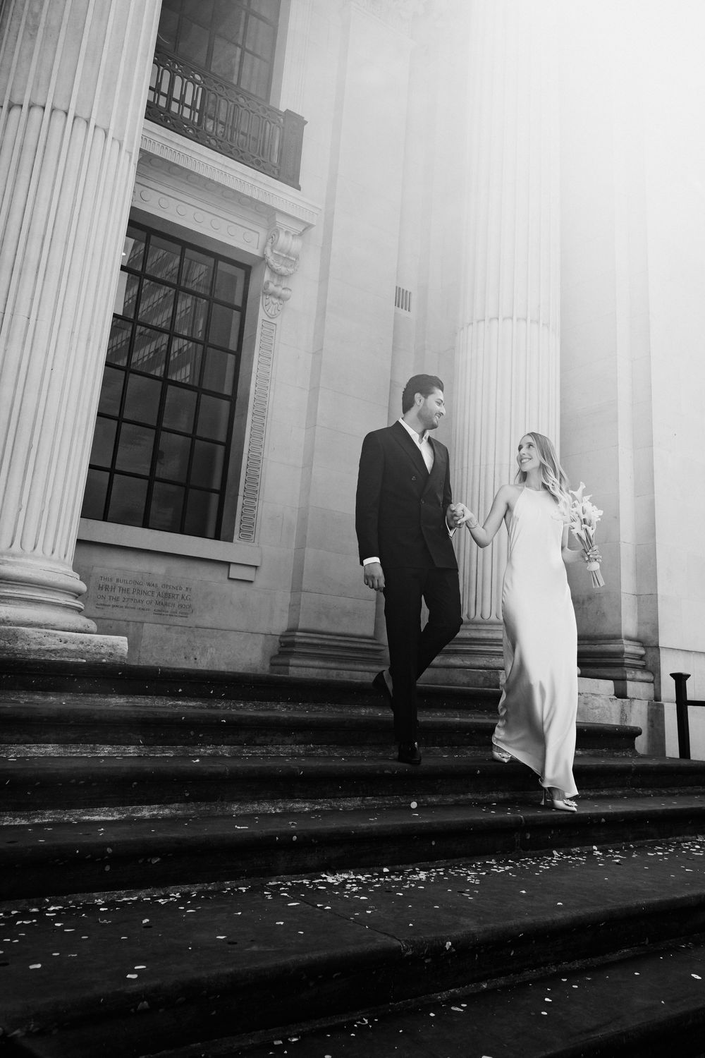 Black and white wedding photo with couple by classical columns and architecture.