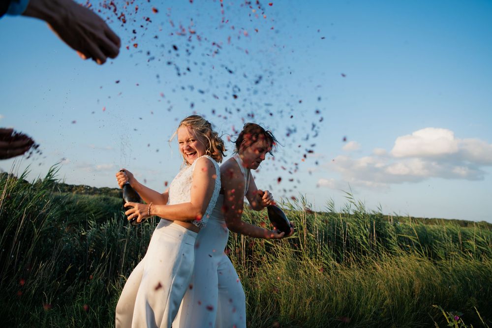 Confetti floating in blue sky over green field during outdoor celebration.