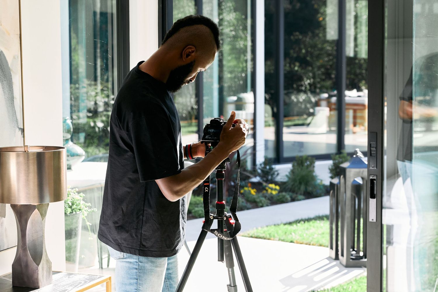 Photographer setting up camera equipment on tripod by window.