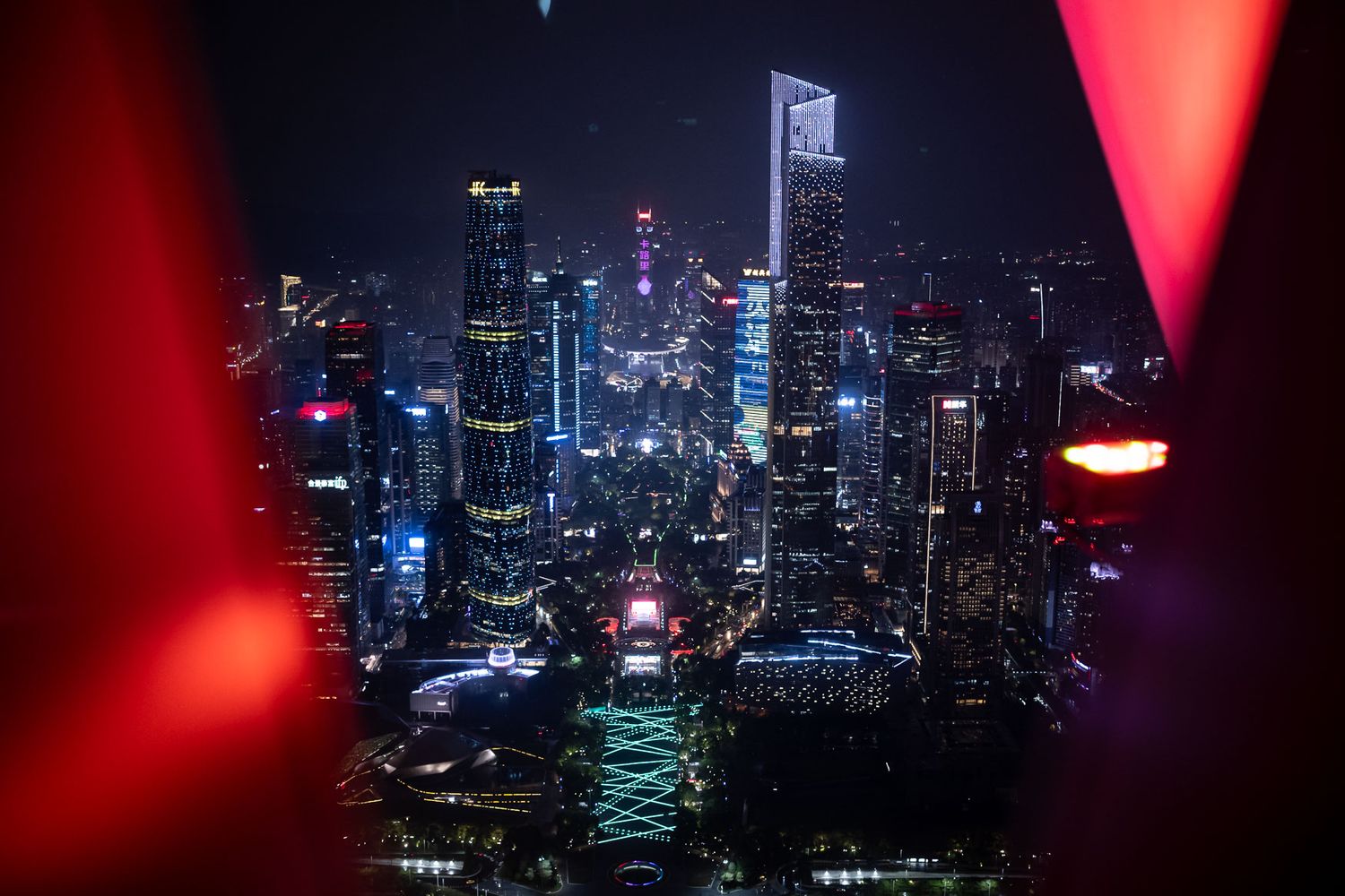 Futuristic cityscape with neon lights framed through red-tinted window or lens.