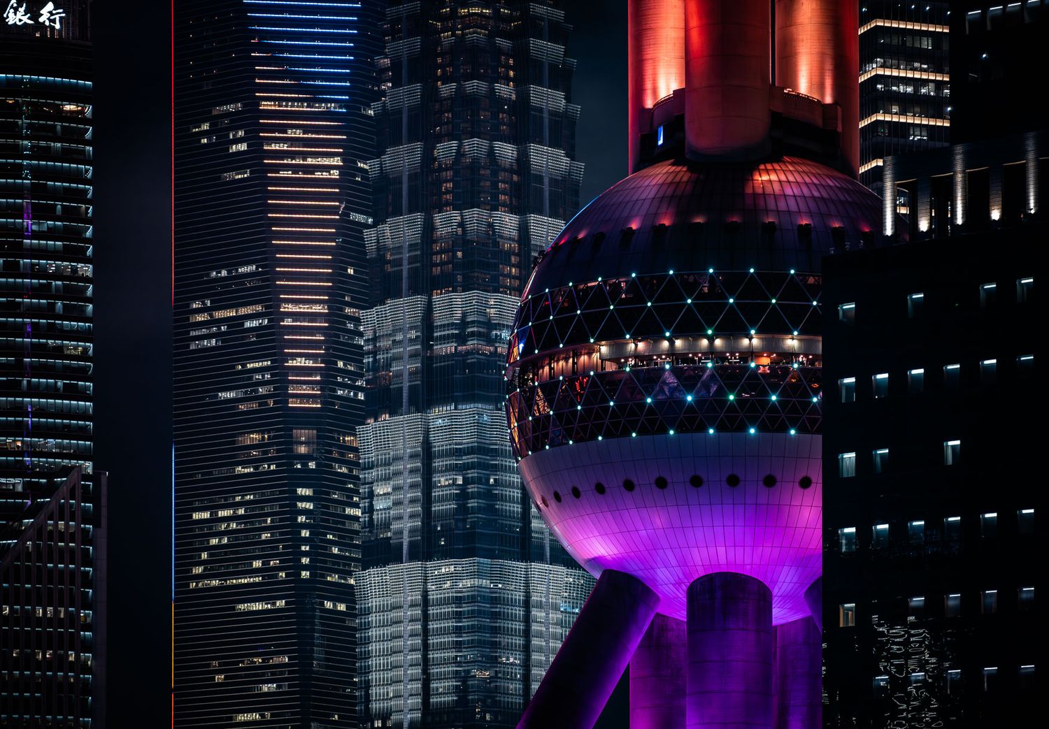 Illuminated Oriental Pearl Tower glows purple against Shanghai's modern cityscape at night.
