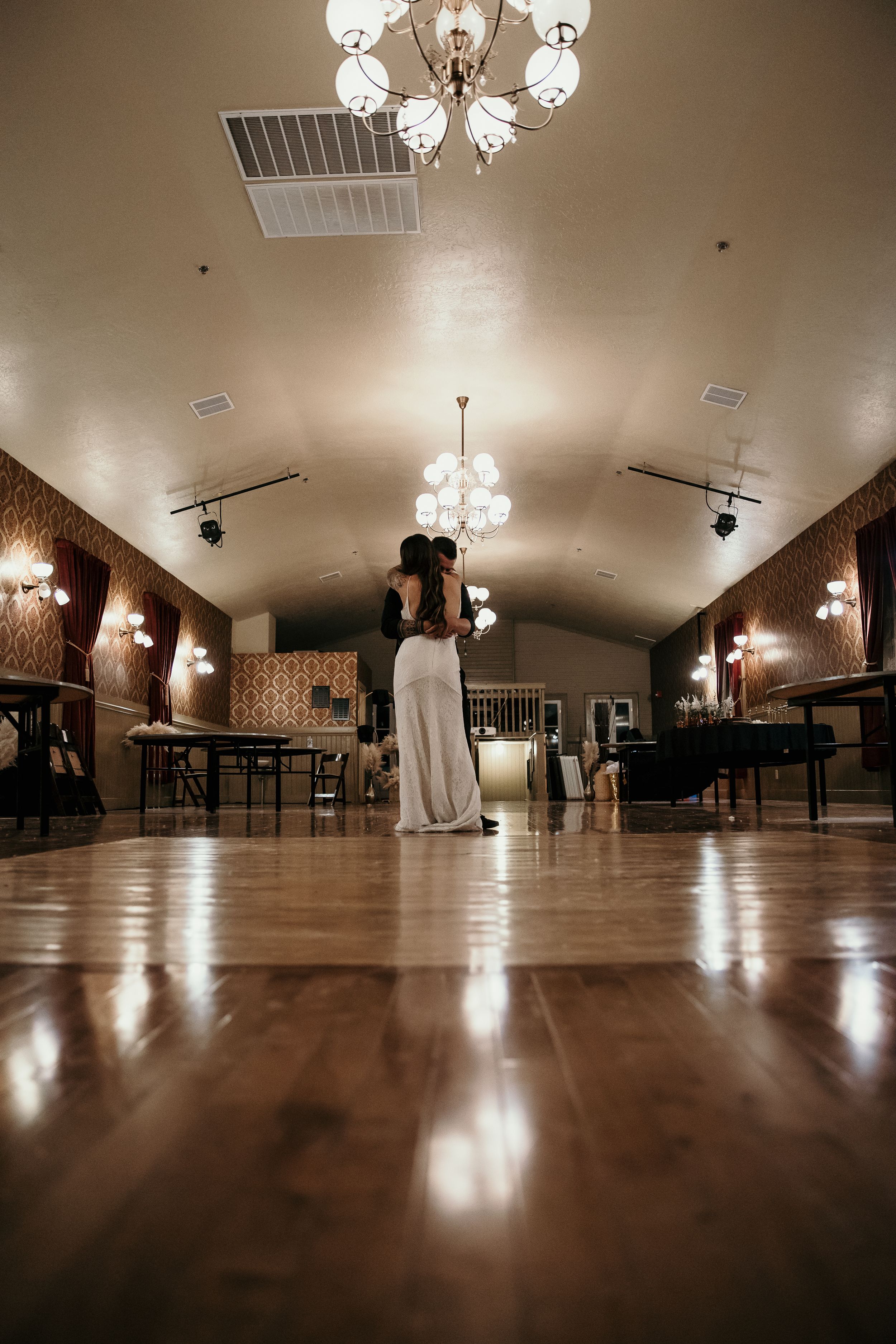 A panoramic view of an elegant ballroom with chandelier lighting and polished wooden floors.