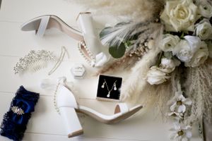 Wedding accessories flat lay with white shoes, tiara, jewelry and roses on light background.