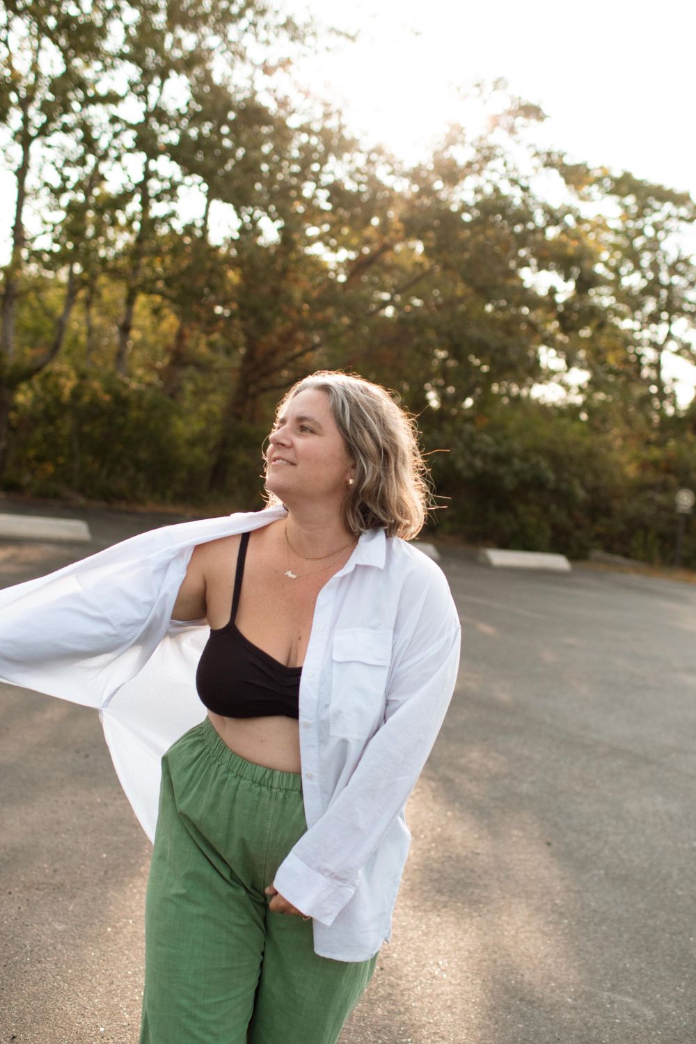 Casual outdoor portrait with white shirt and green pants in golden sunlight.