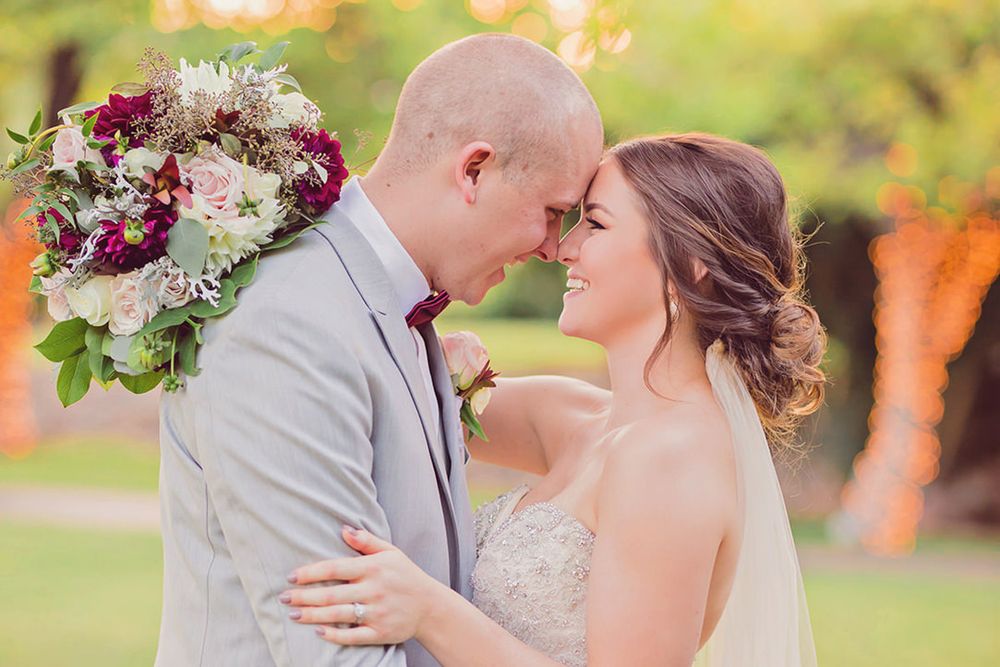 A couple shares a romantic moment in a garden setting surrounded by autumn colors and floral bouquets.