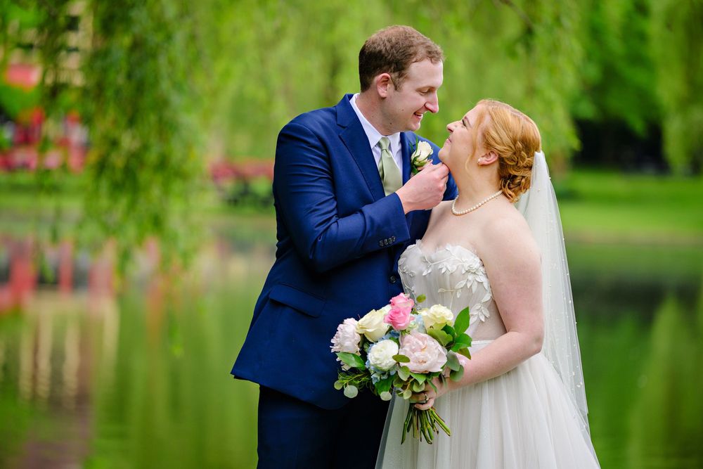 Bride and groom standing in front of a pond at Gervasi Vineyard before their wedding in the pavilion on a rainy day in Canton Ohio