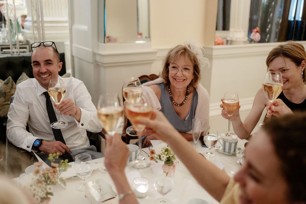 A group of people raise their glasses in a celebratory toast at a bright, elegant dining room.