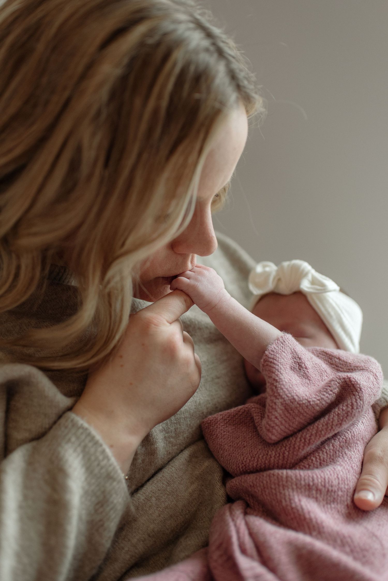 A newborn baby wearing a cozy brown knitted bear outfit lies on a textured blanket during a professional photo session.