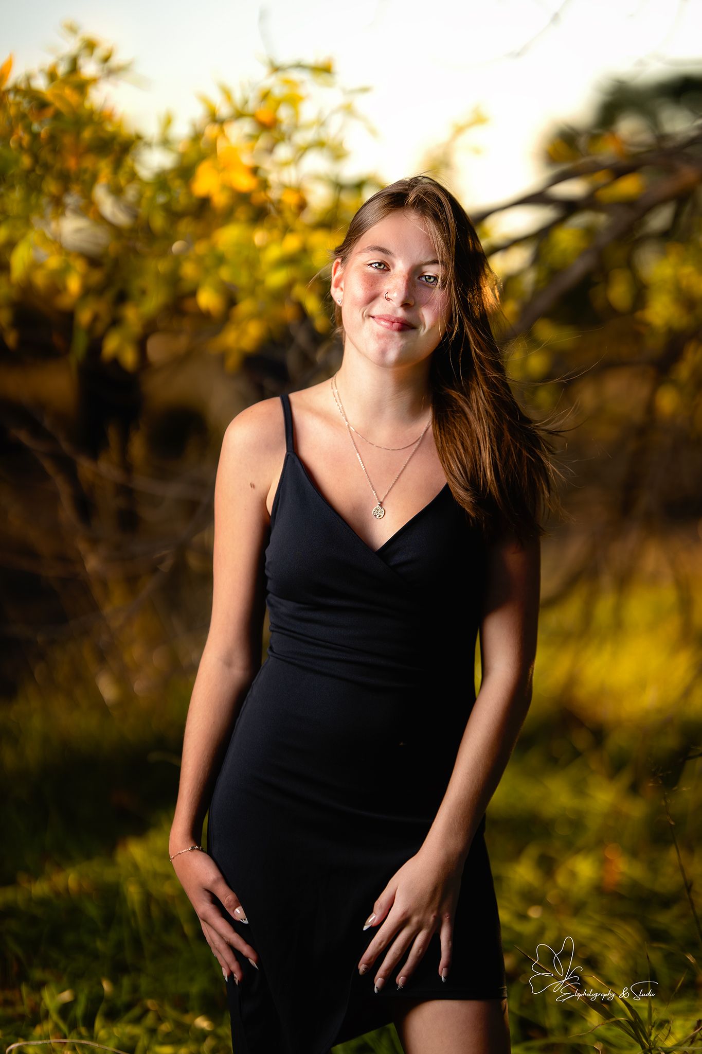 Portrait series of person in black dress against golden sunset background with autumn foliage in Pierre, South Dakota.