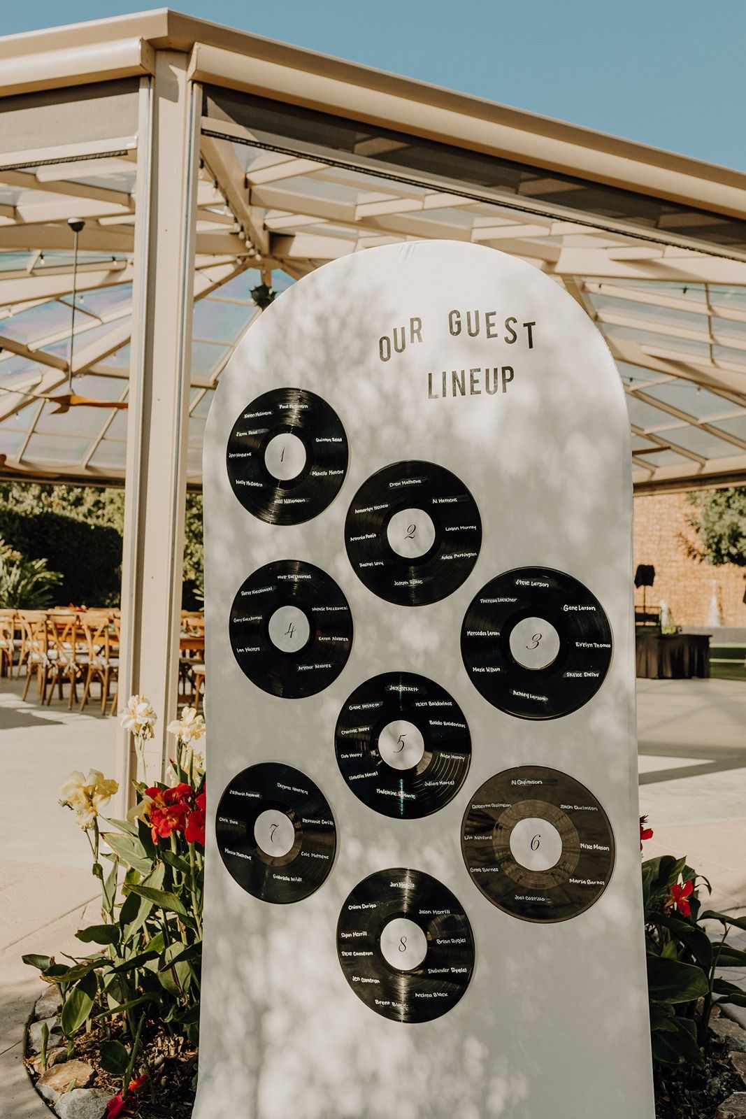 Wedding seating chart display with vinyl record-inspired design against white backdrop at River Garden Weddings and Events.