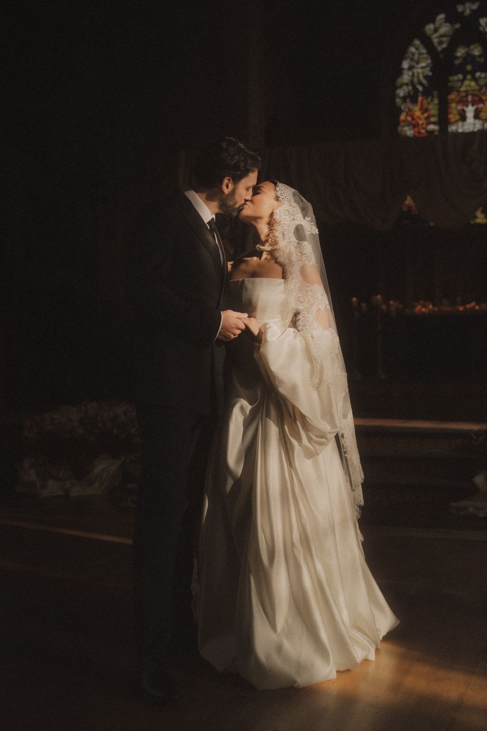 A couple shares a romantic dance moment in wedding attire under dramatic lighting at their reception.