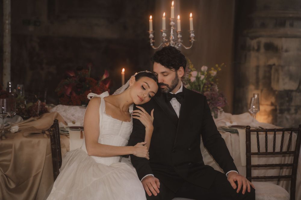A romantic candlelit wedding reception scene with a couple seated at an elegant table setting.