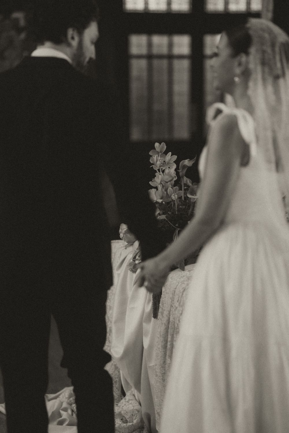A black and white wedding photo showing a couple during their ceremony with delicate floral details.