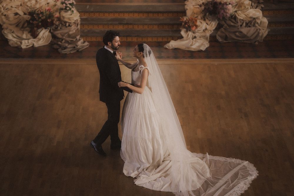 A couple shares an intimate dance moment in a rustic venue with warm lighting and stone walls.
