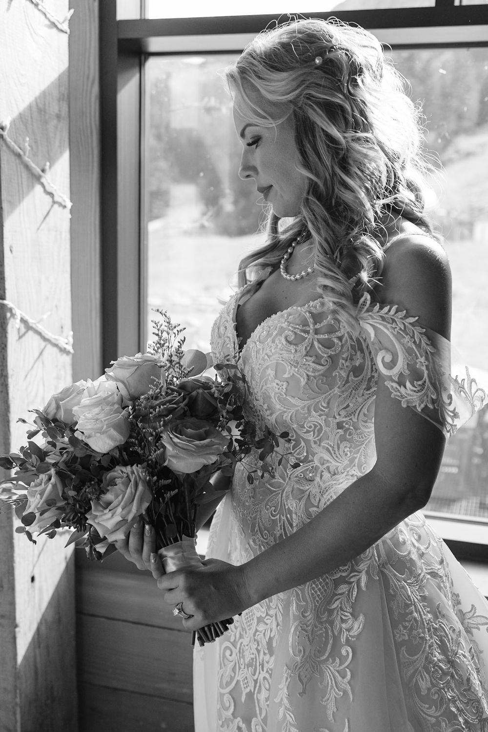 Black and white photo of bride admiring her wedding bouquet.