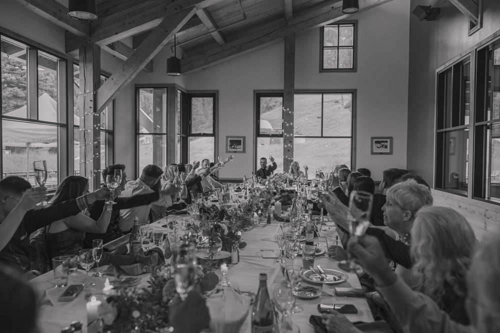 Bride and Groom toast to their guests at wedding during family-style seating.