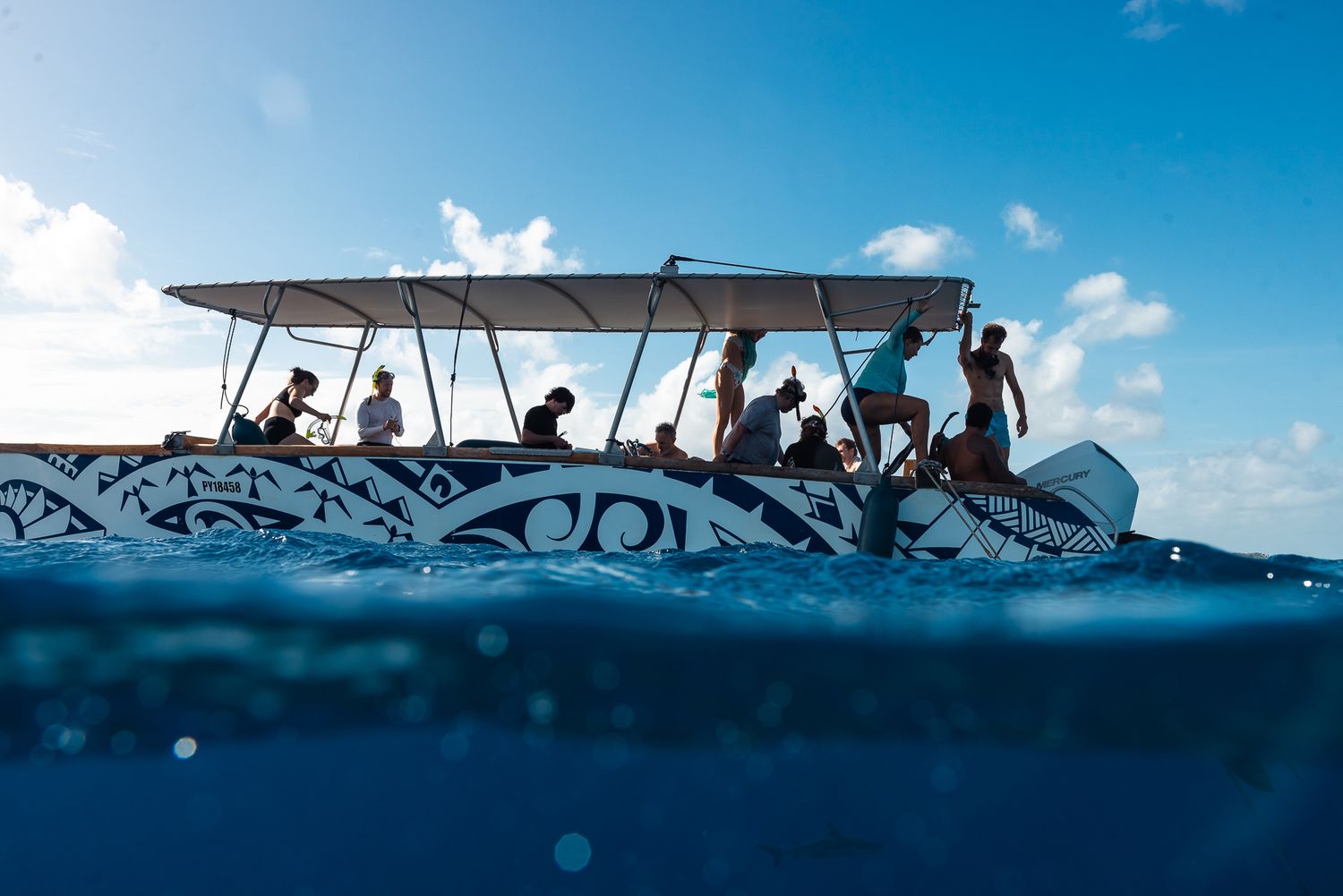 Group of tourists on a decorated boat at sea, captured from water level under a blue sky.