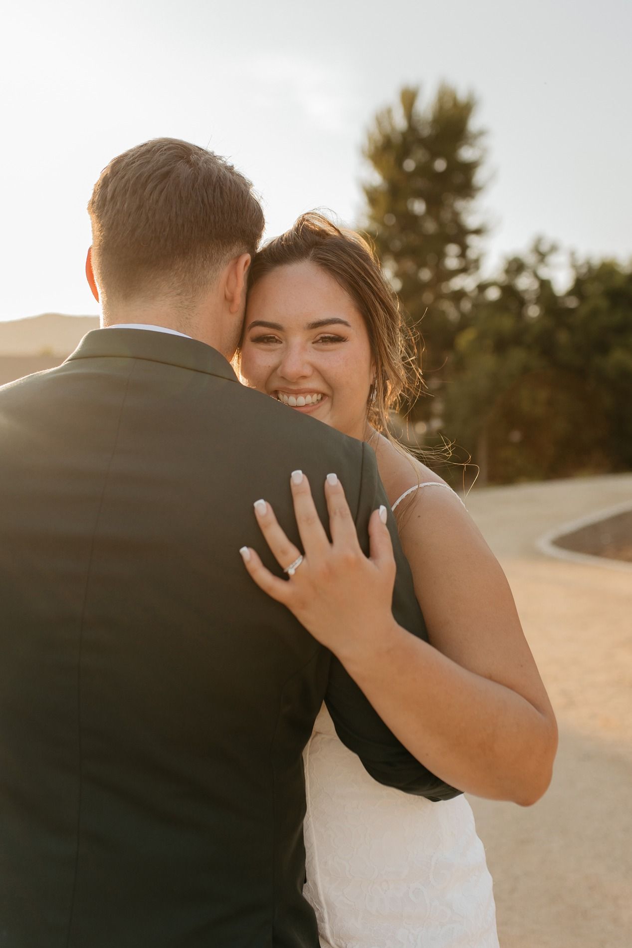 A couple embraces intimately during their golden hour wedding photo session in a desert landscape at Canopy Grove by Wedgewood Weddings.