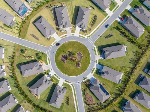 Aerial view of suburban neighborhood with winding streets and green lawns captured from a drone perspective.