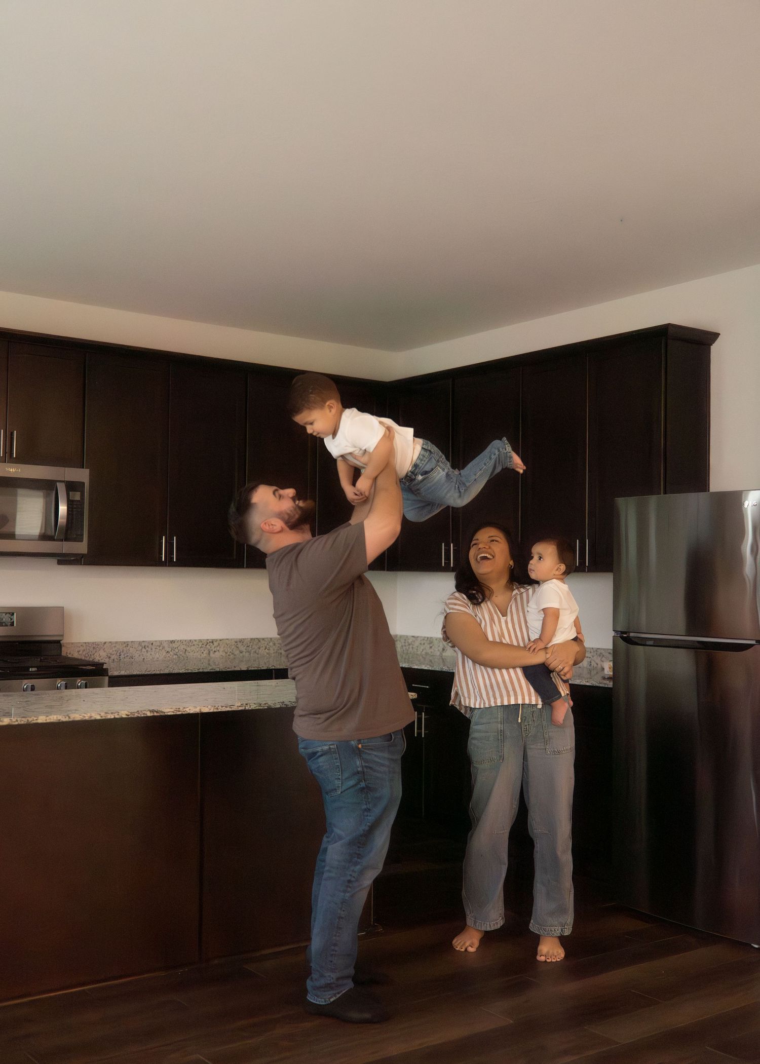 The Emerson Family of five posing in their empty new home, smiling and exploring their new space together