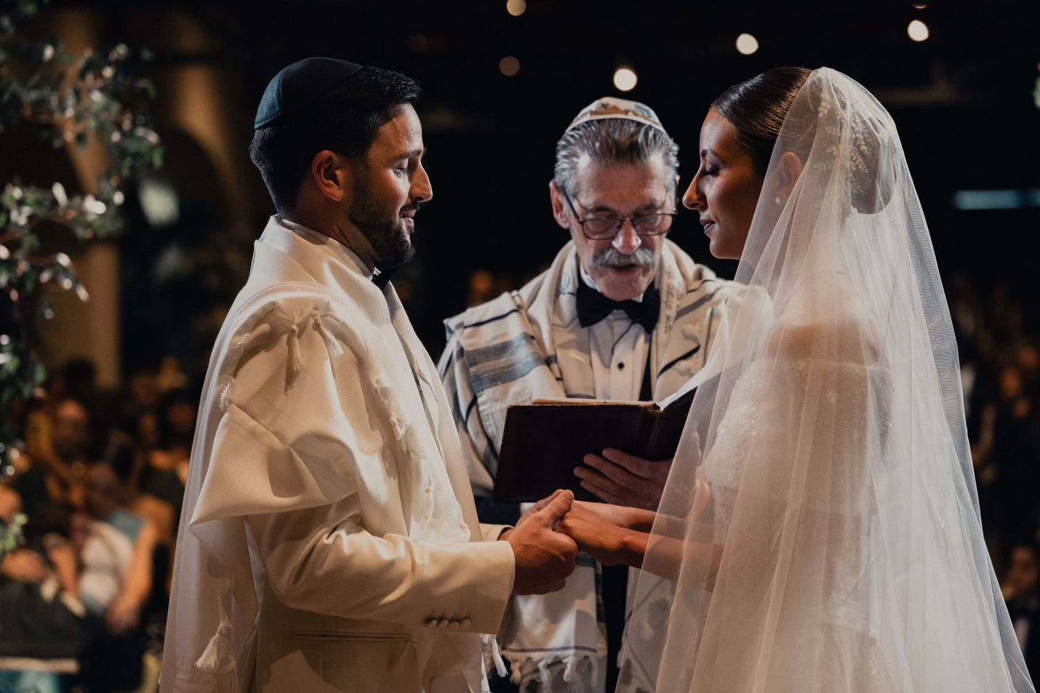 A couple exchanges rings during an intimate wedding ceremony with bokeh lights in the background.