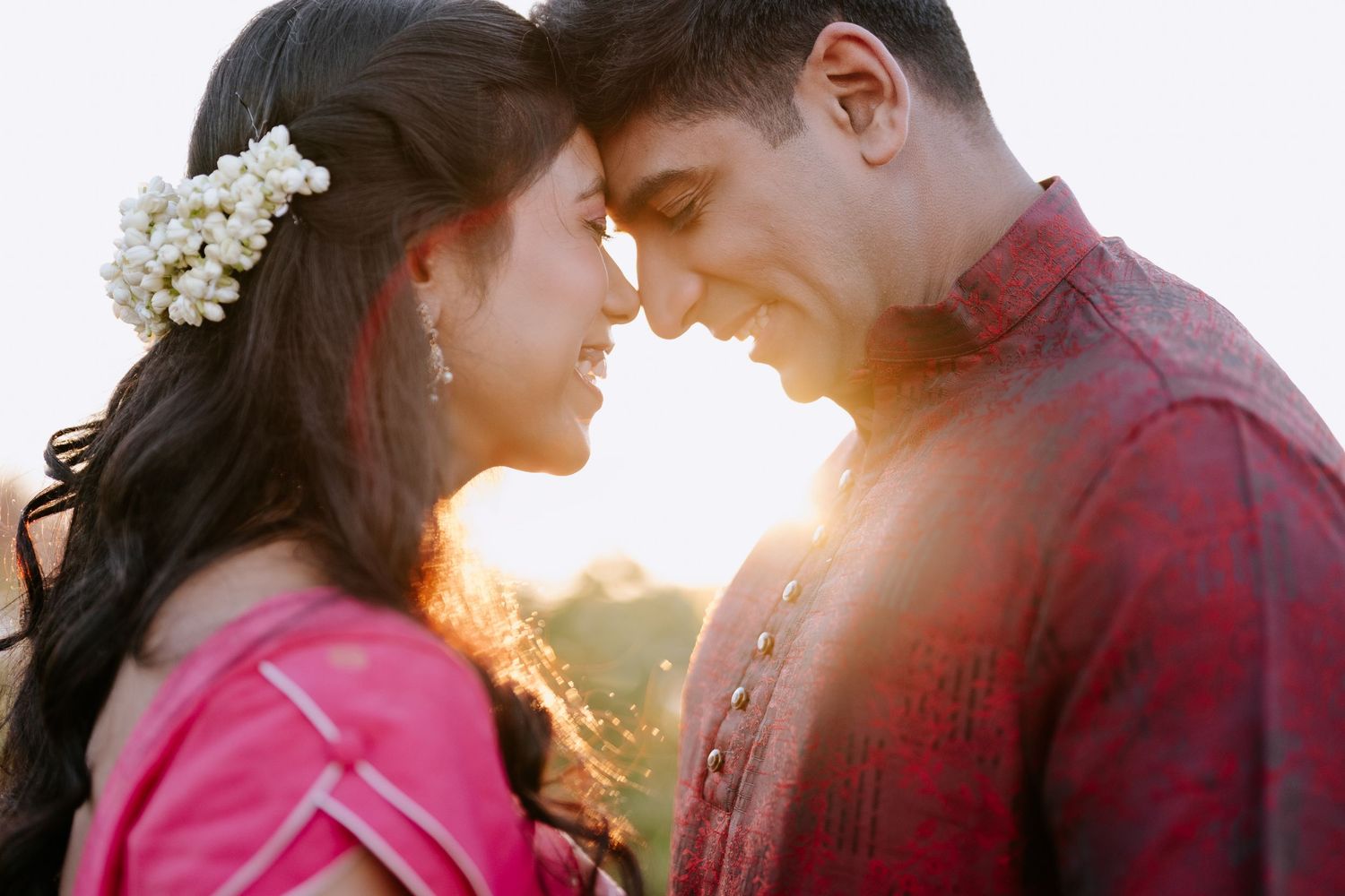 A couple in coordinated purple outfits poses together in an outdoor stone setting for engagement photos.