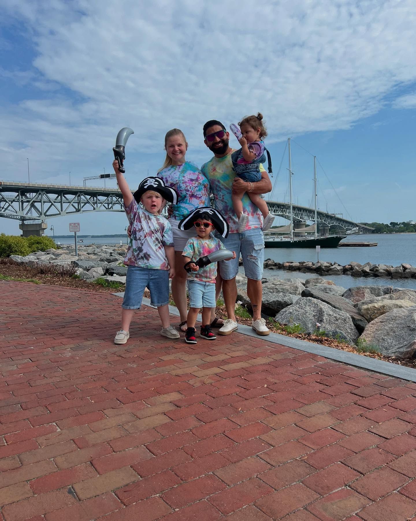 family wearing tie dyed shirts wtih pirate swords and hats on the riverwalk in yorktown virginia for the annual pirates invasion