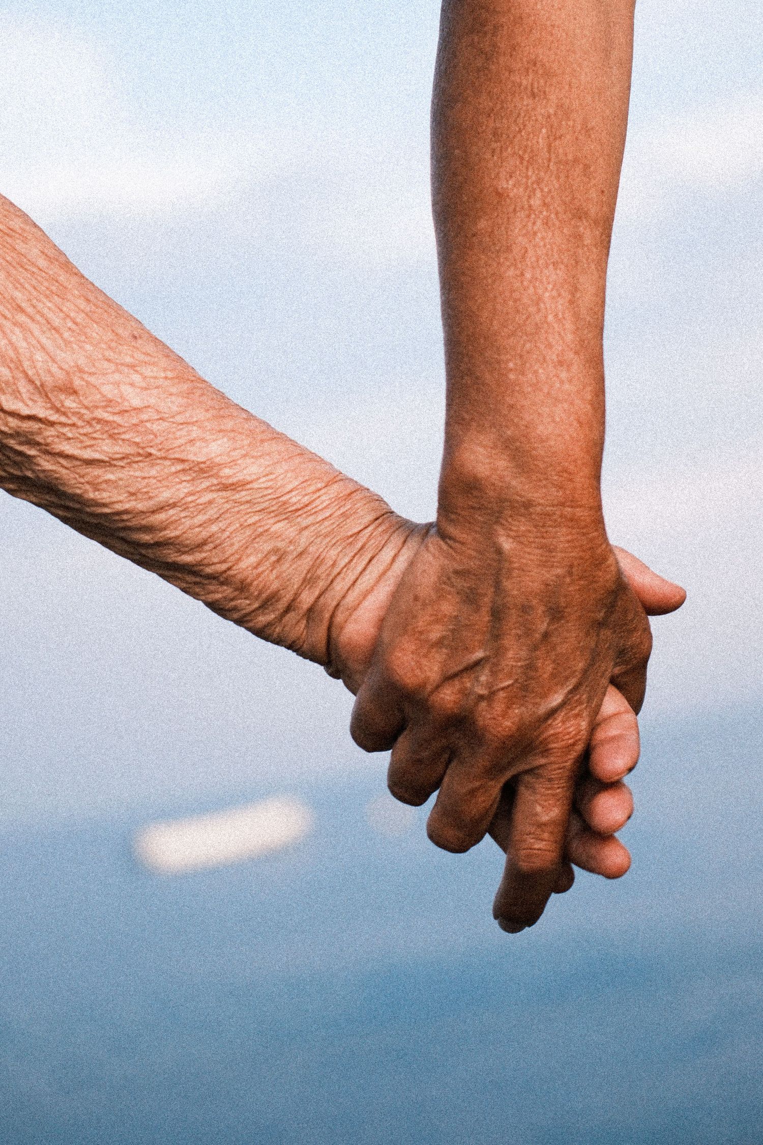 A sequence of photos showing two elderly hands clasped together against a blue sky background.