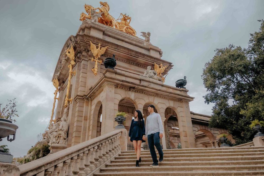 Couple holding hands walking through the gardens as sky turns gray.