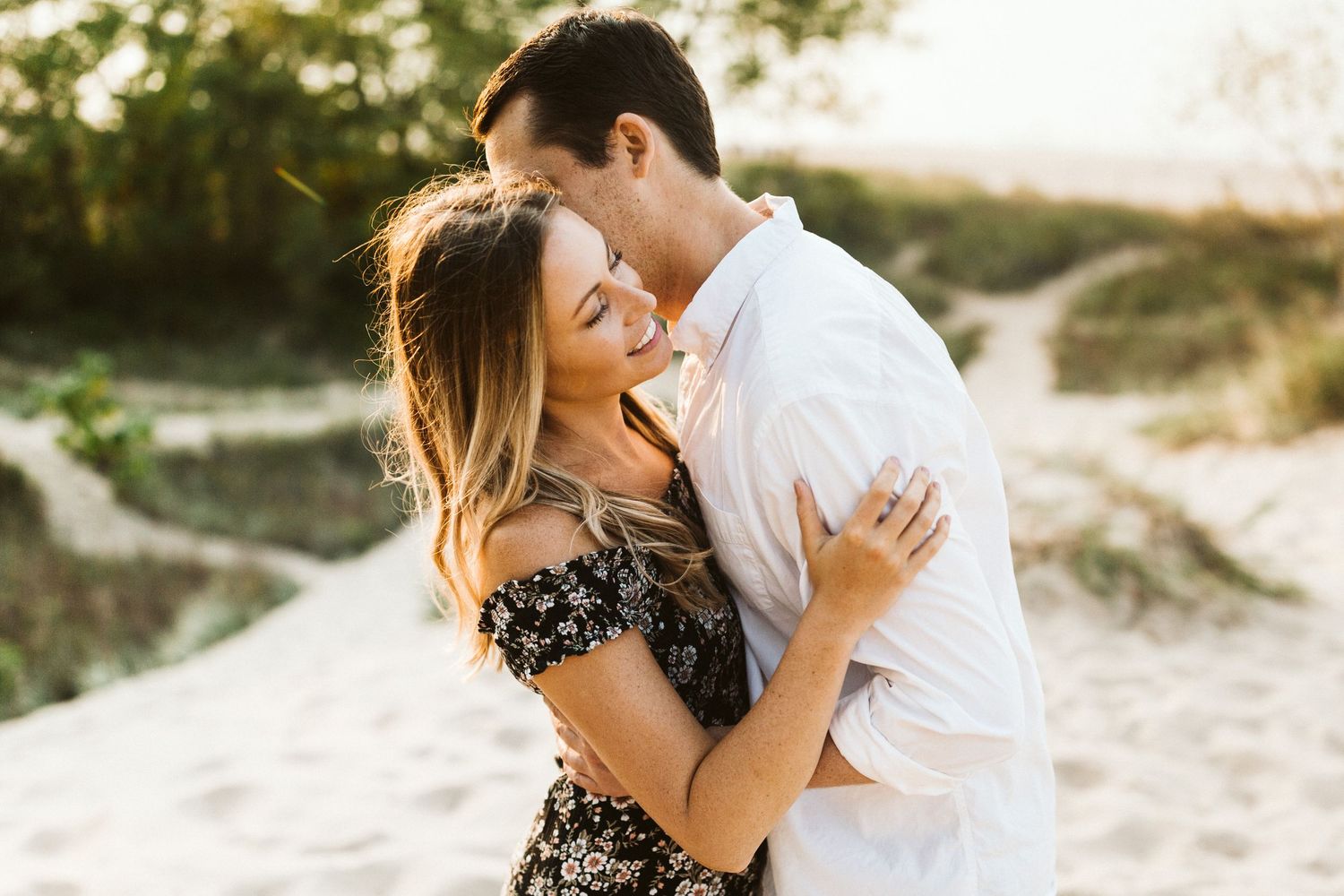 A couple shares intimate moments on a sandy beach during a romantic sunset photo session.