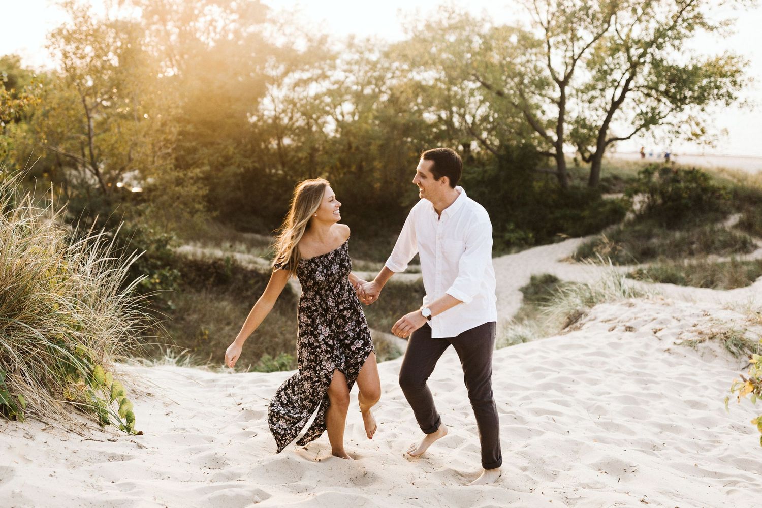 A couple shares romantic moments together during a sunset photoshoot on a sandy beach path.