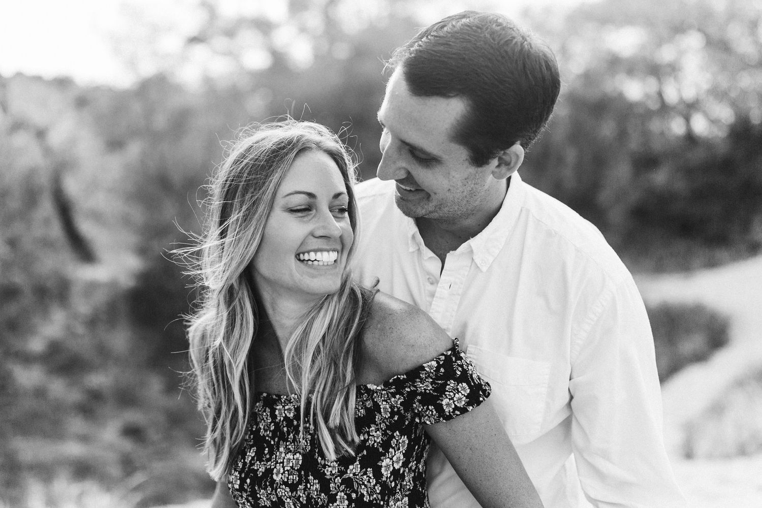 Black and white photo of a couple sharing an intimate moment on a beach path.
