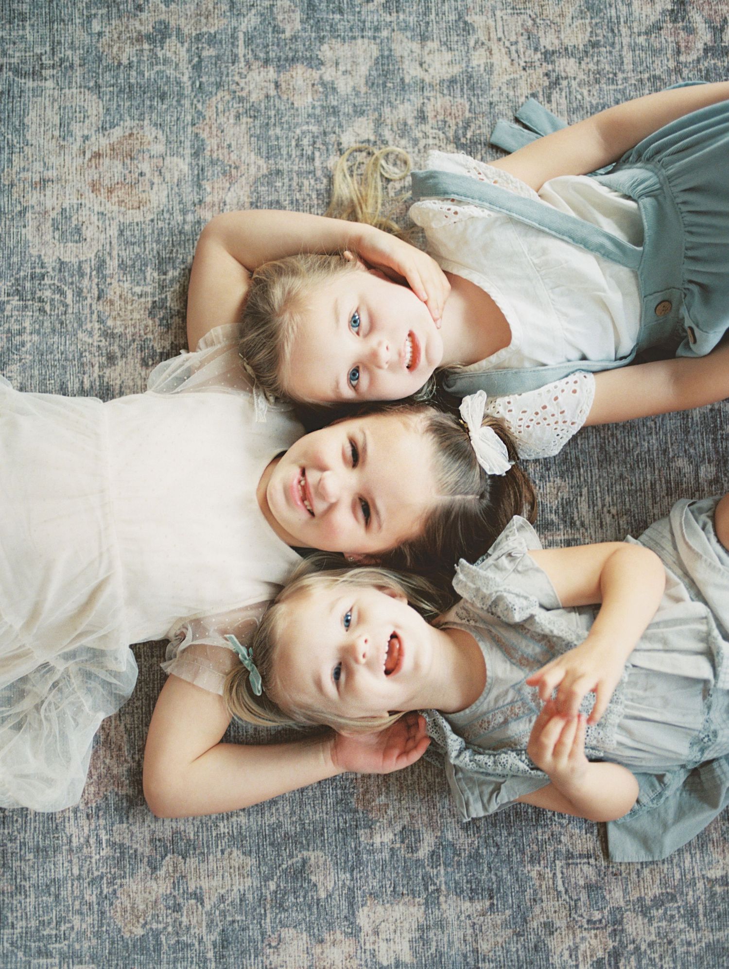 A series of five portrait photos showing a person in a light colored dress laying on a textured gray floor.