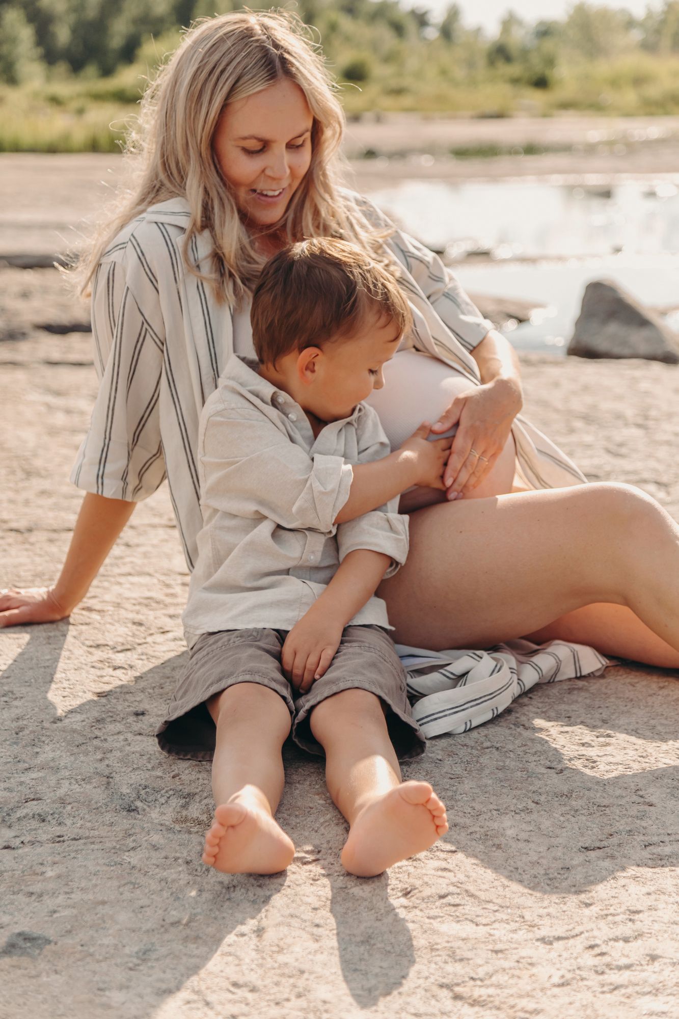 A tender moment between parent and child sitting together on a sandy beach in soft natural light.